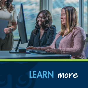 two women in business clothes looking at monitor